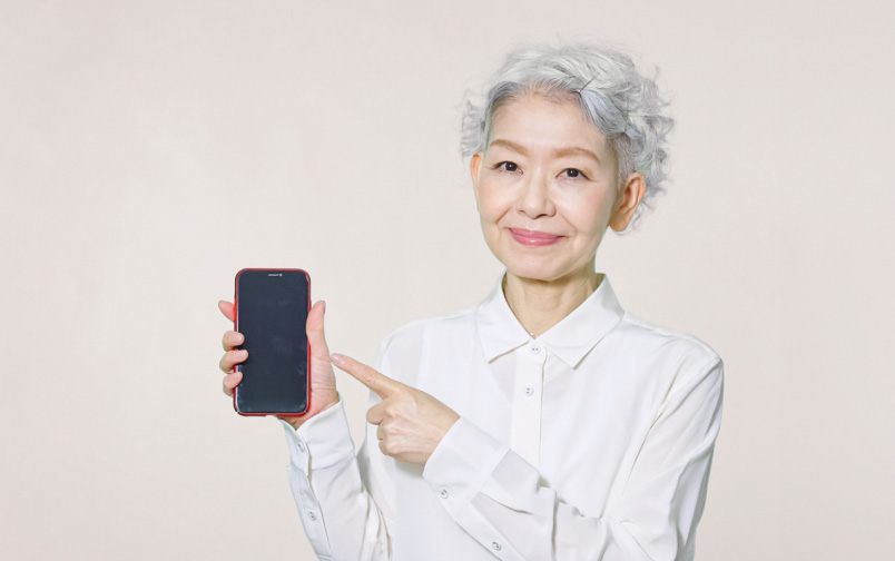 スマートフォンを指差す高齢者の女性